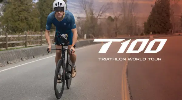 A determined athlete cycles on a road, preparing for the T100 Triathlon World Tour.