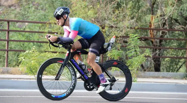 Athlete in aerodynamic position on a triathlon bike, training for a race.