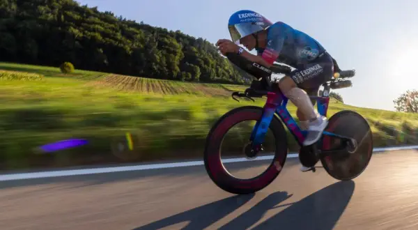A cyclist in an iron man race powers through a scenic countryside, the blur of motion highlighting their intense effort.