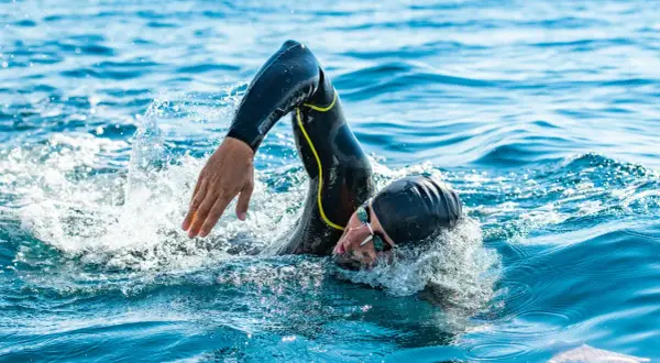 Athlete in wetsuit swims powerfully, a testament to the journey from couch to triathlon.