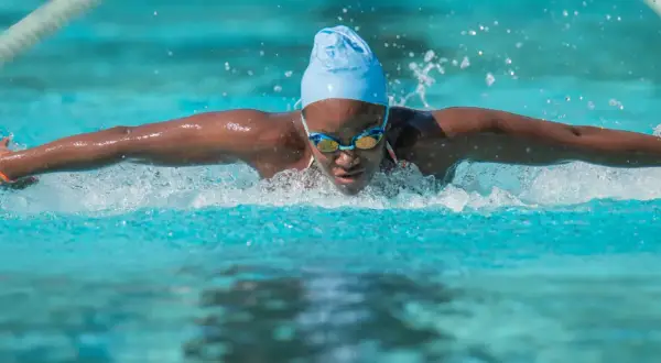 A swimmer powers through the water, a blur of motion and spray. This intense workout is a great way to burn swim calories.