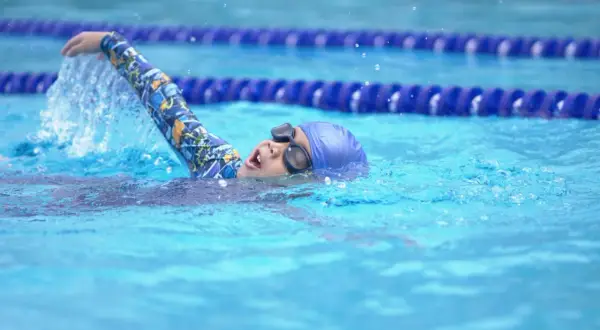 A young swimmer practices the side stroke, their arm slicing through the water.