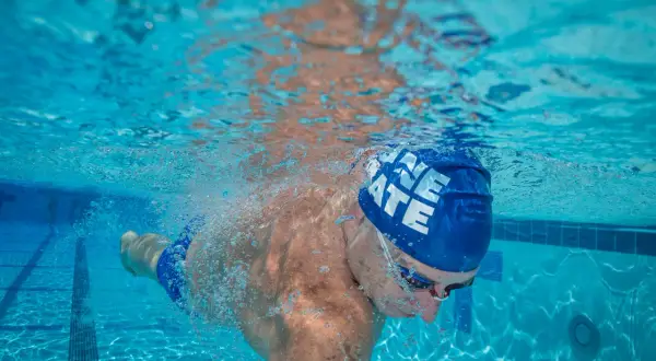 Underwater view of a swimmer's powerful swimmer lats as they glide through the blue water, bubbles trailing behind.