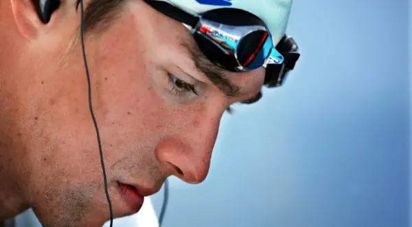 Michael Phelps in deep visualization, wearing Speedo cap and goggles, preparing for a race.