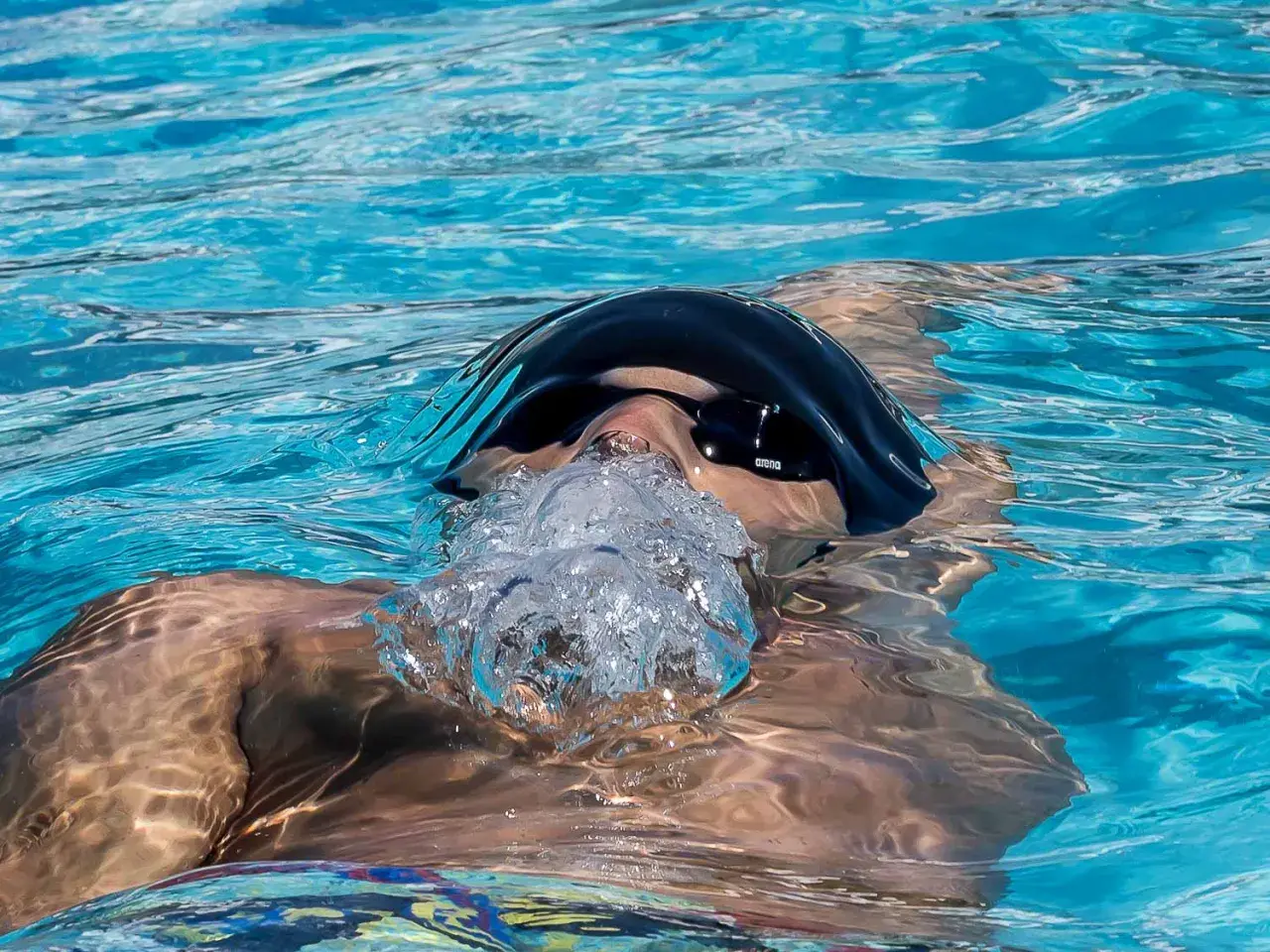 A swimmer exhales bubbles, showing that you can swim with a scraped knee.