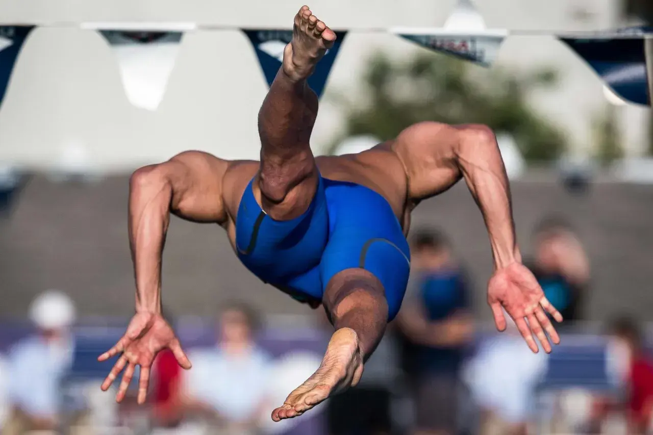 A swimmer in mid-air, showcasing the powerful back muscles developed through dedicated back exercises.