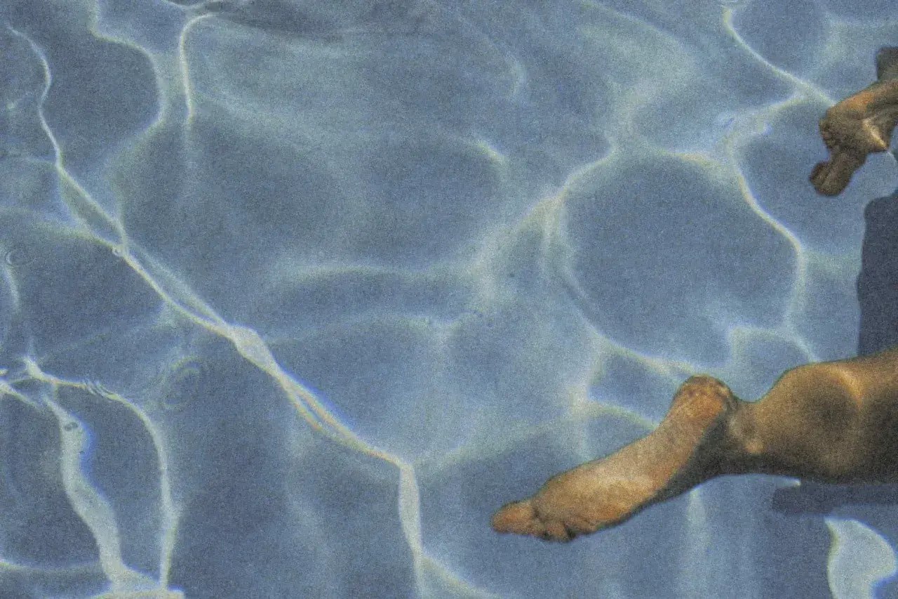 Sunlight dances on the water's surface, illuminating submerged feet. Does chlorine kill yeast on skin? This pool might offer an answer.