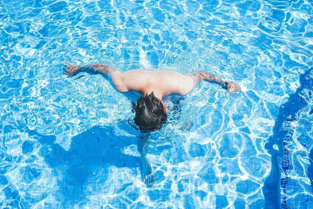 A person swims in a bright blue pool. Wondering how often should I swim? This refreshing activity is great for fitness.