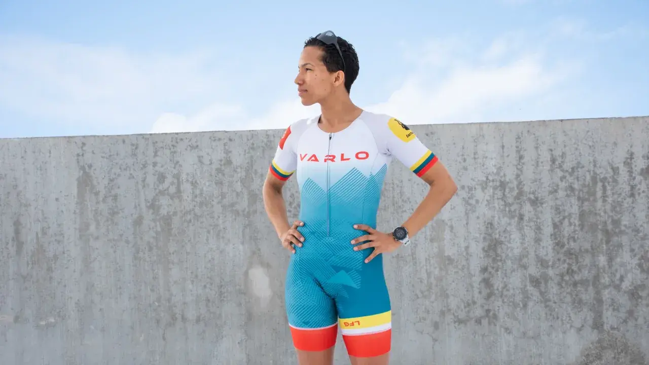 A woman in a vibrant blue and white triathlon suit, ready for competition. This is what to wear for a triathlon.