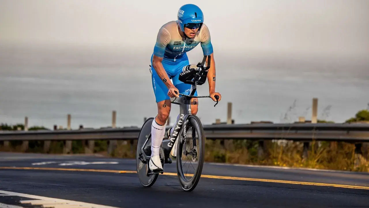 A determined triathlete, perhaps a beginner, races on a bike, focused on the road ahead.