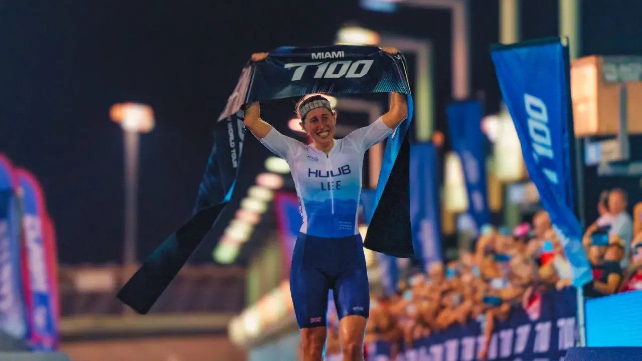 India Lee celebrates a victory, holding up a "Miami T100 World Tour" banner.