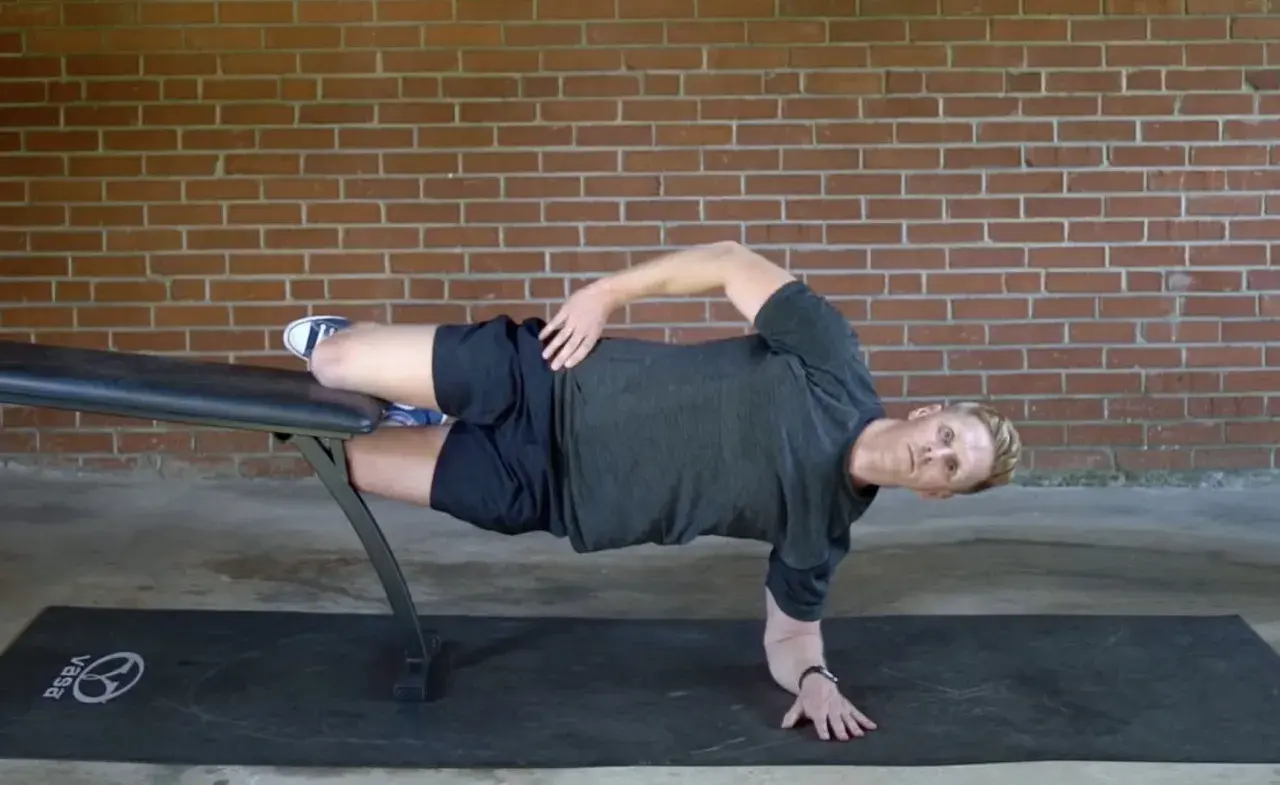 Man performing a side plank on a bench, a key exercise for core workouts for swimmers.