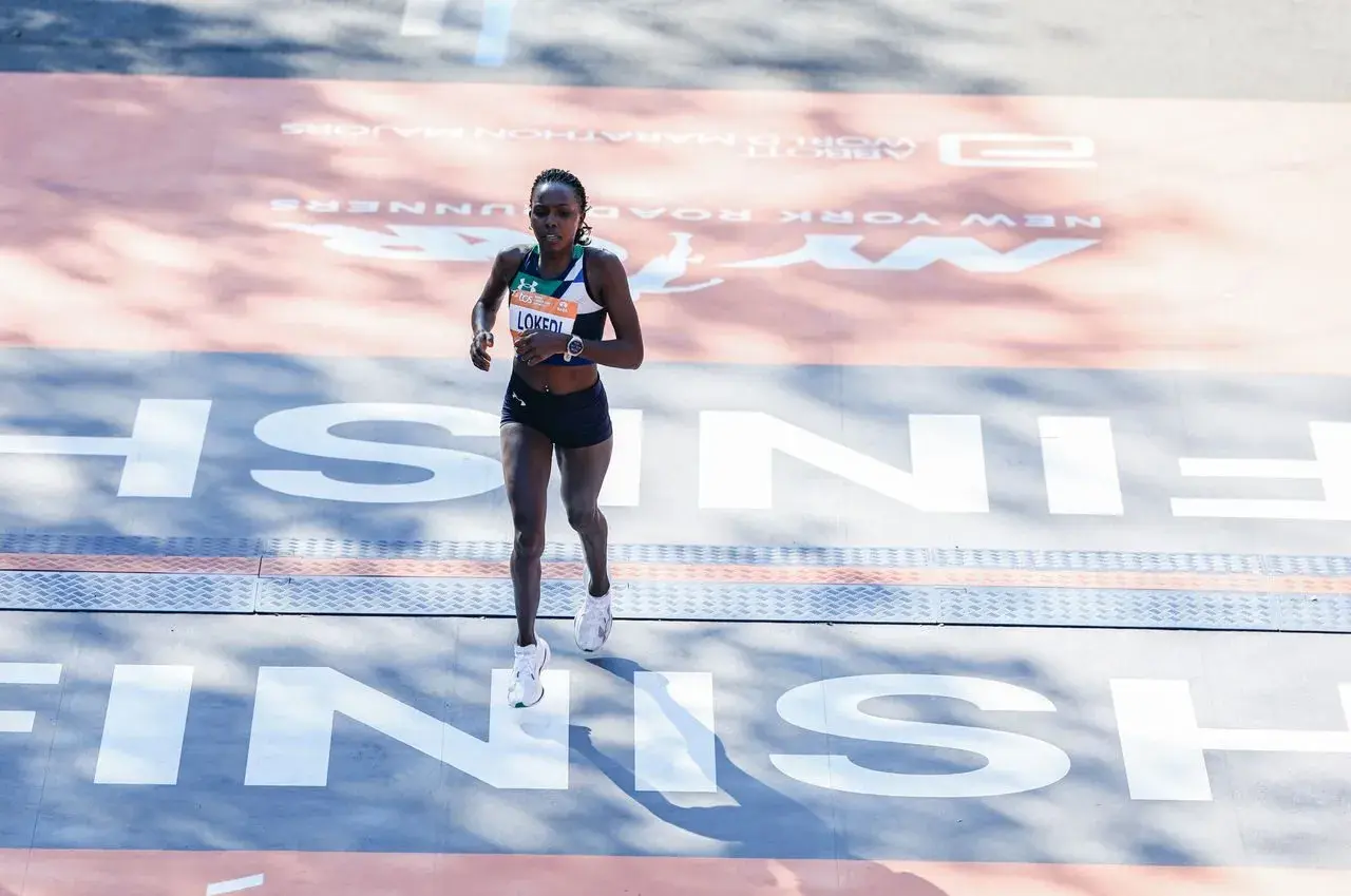 Runner crosses the finish line in her Under Armour tri suit, a testament to her endurance and dedication.