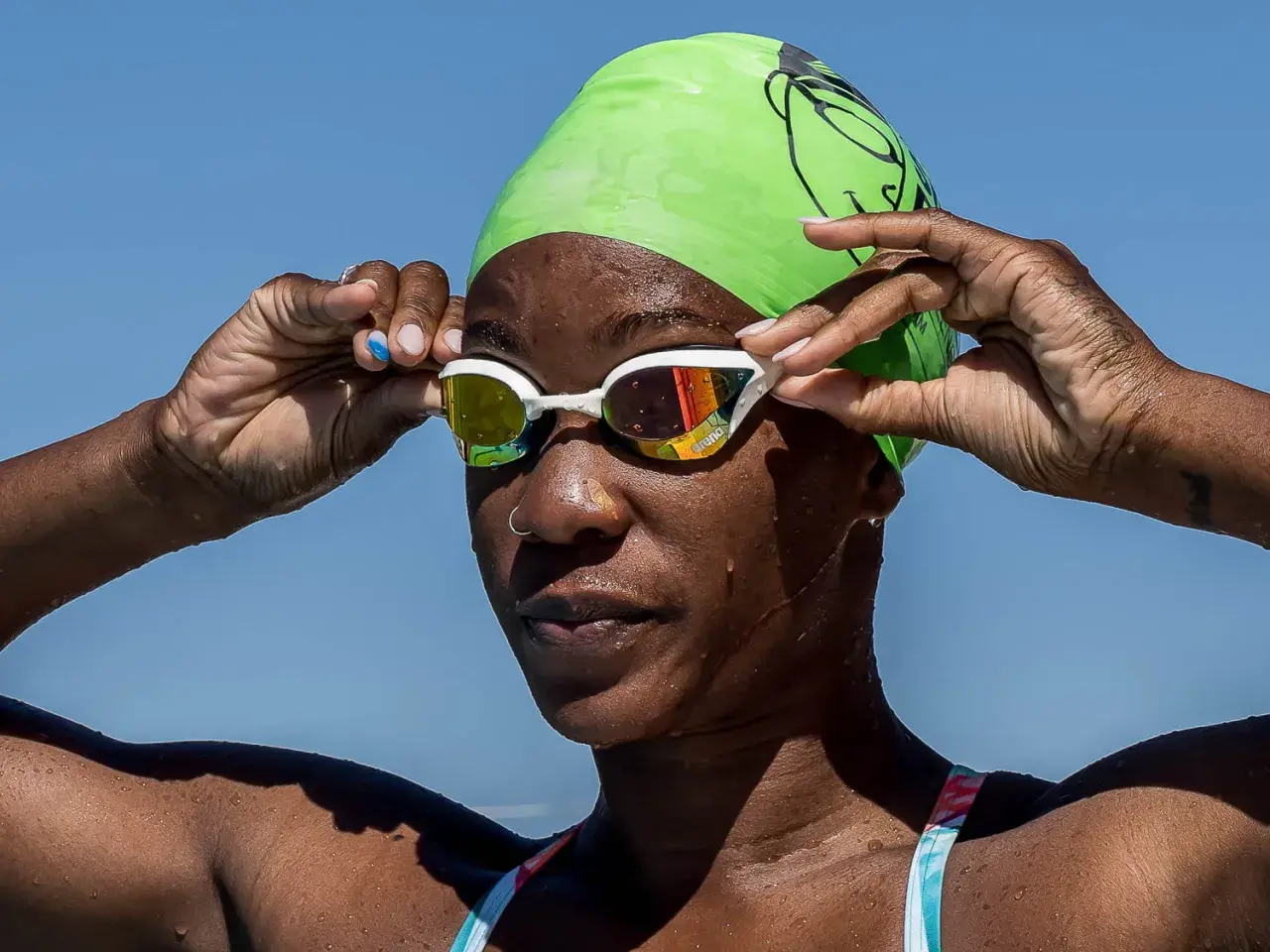 A swimmer adjusts her goggles, ready to dive in. She's proving you can swim with a burn, embracing the water.