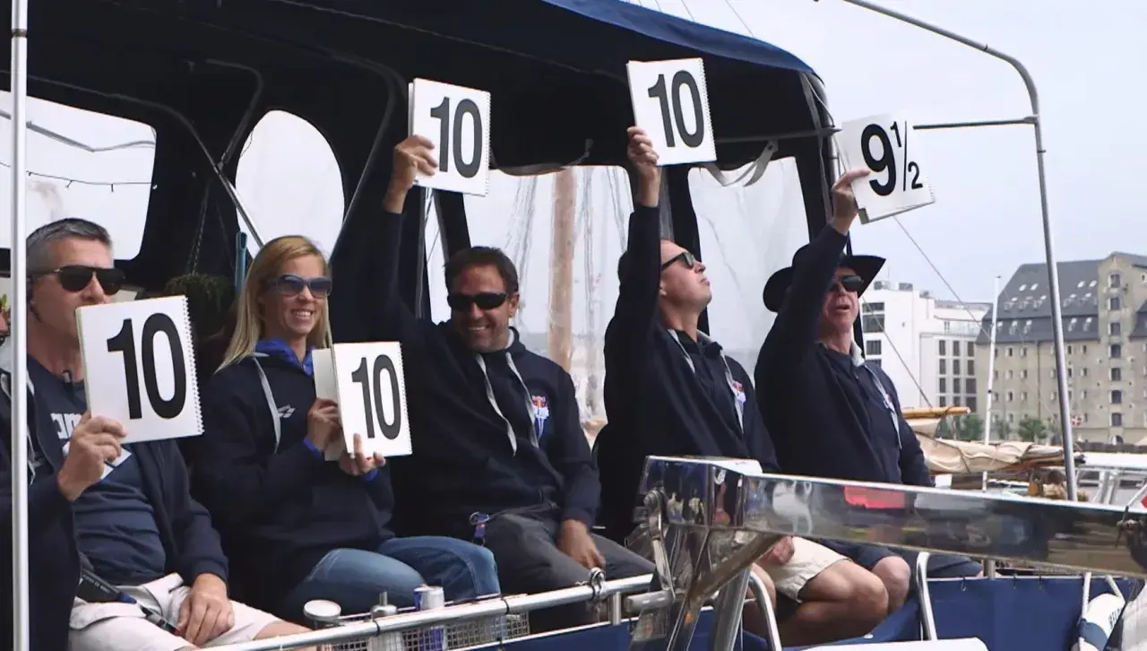 Judges hold up scorecards showing "10" and "9 1/2", indicating high diving scores.