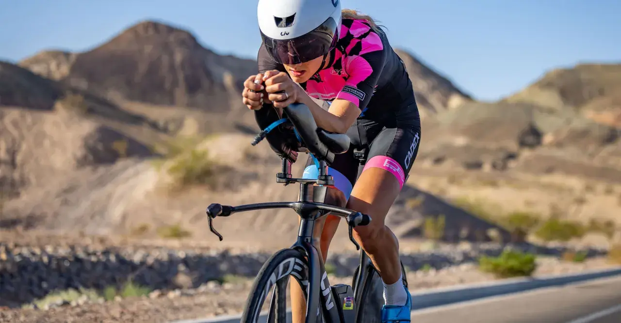 A determined woman competes in a womens triathlon, cycling intensely through a desert landscape.