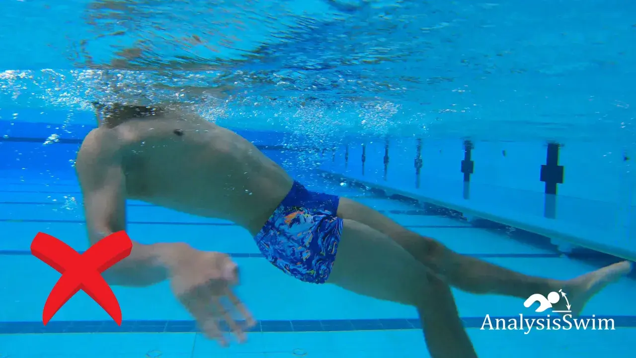 Underwater view of a swimmer demonstrating an incorrect backstroke arm movement. A red X marks the improper arm position.