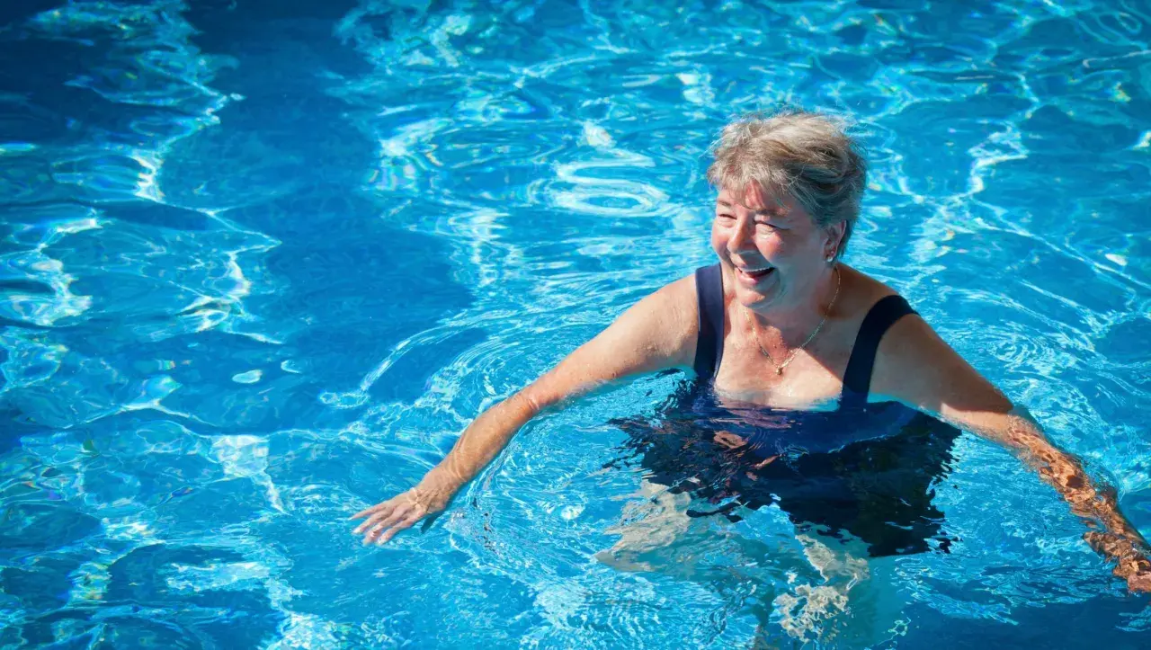 Smiling woman enjoys a refreshing swim, proving you can swim with a pacemaker and live life to the fullest.