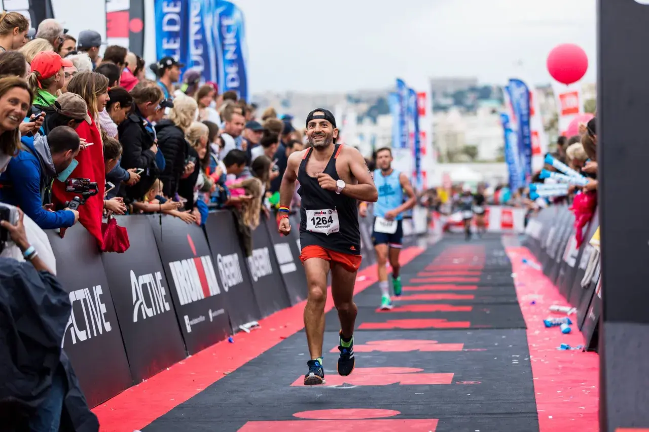 A determined runner approaches the Ironman finish line, cheered on by a crowd.