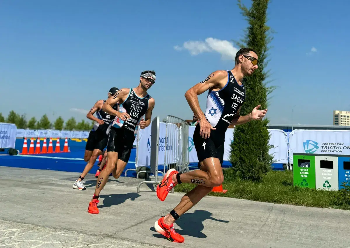 Athletes in racing gear push forward during a triathlon training run, focused and determined under a bright blue sky.