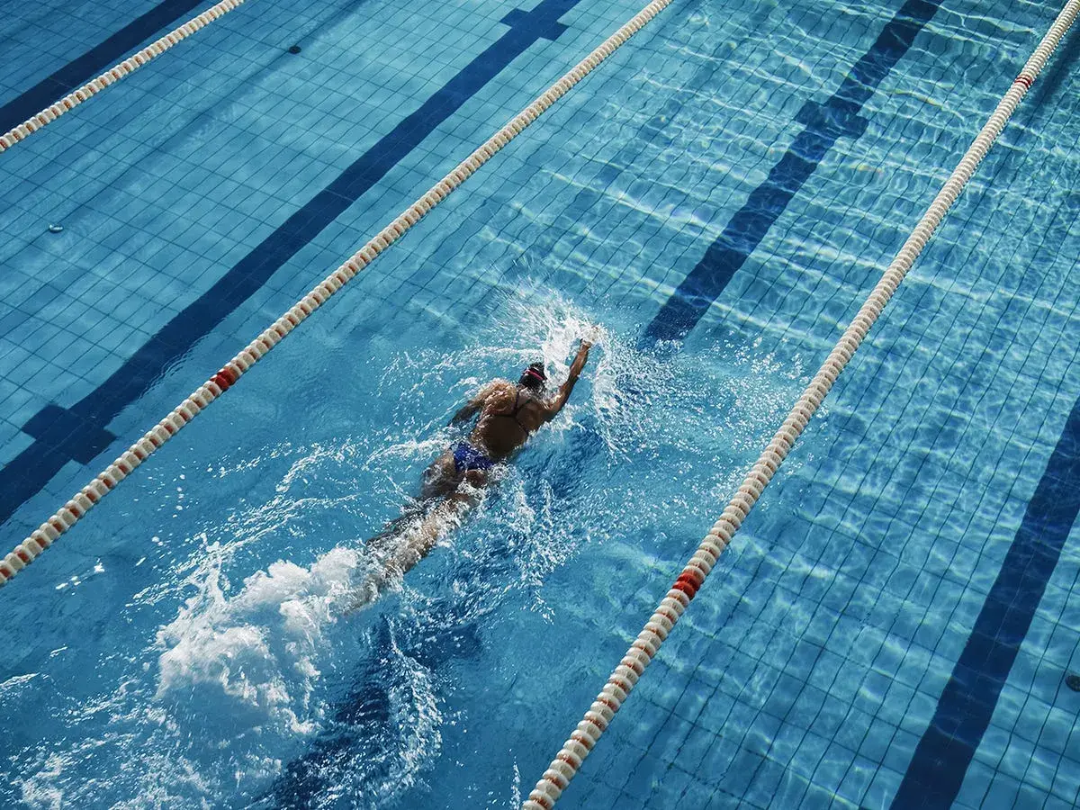 Swimmer powering through a lane, a great way to see how many calories do you burn in the pool.