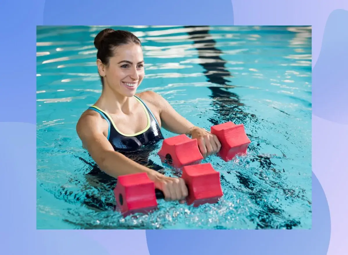 Woman smiling while doing pool exercises for abs with red water dumbbells.