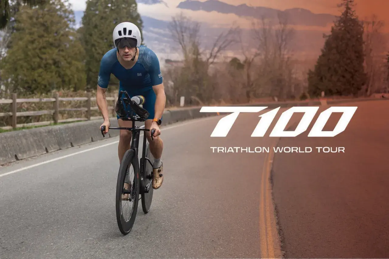A determined athlete cycles on a road, preparing for the T100 Triathlon World Tour.