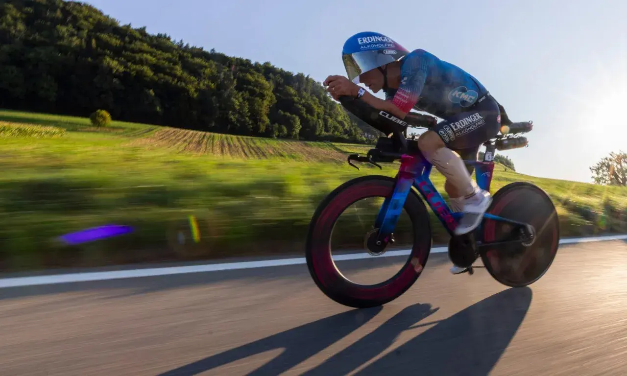 A cyclist in an iron man race powers through a scenic countryside, the blur of motion highlighting their intense effort.