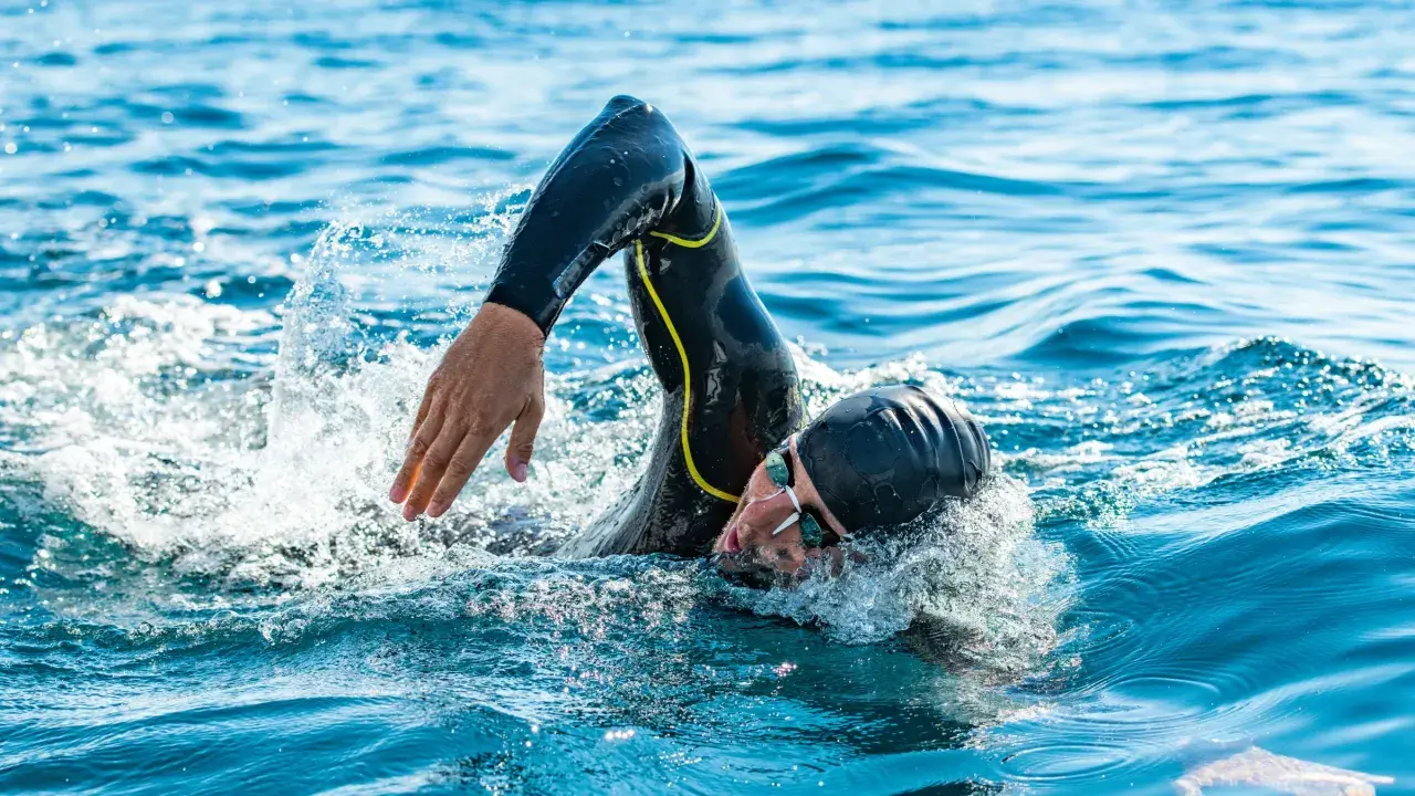 Athlete in wetsuit swims powerfully, a testament to the journey from couch to triathlon.