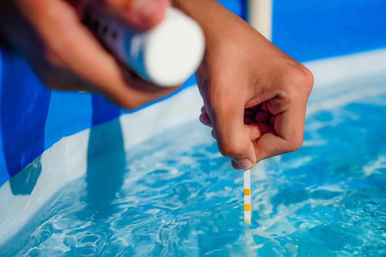 Testing pool water with a strip to see if chlorine kills COVID.