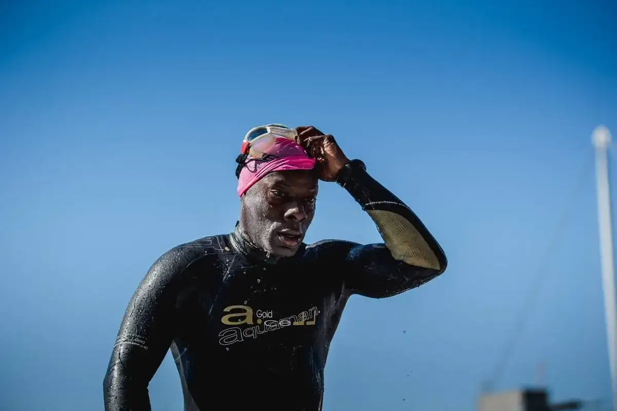 A swimmer in a wetsuit adjusts his goggles, ready for the 70.3 Vineman race.
