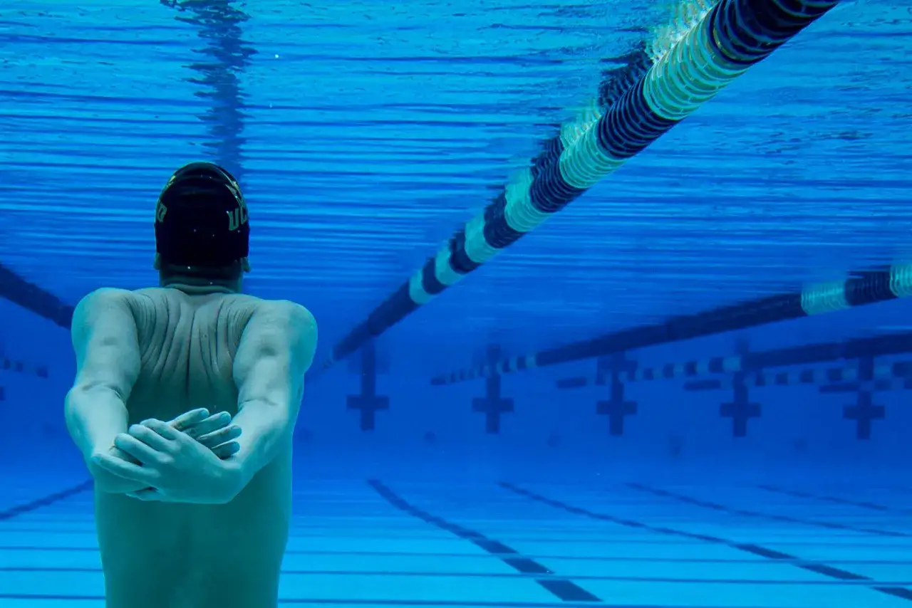 Underwater view of a swimmer stretching arms. Learn how to protect skin from chlorine for a healthier swim.