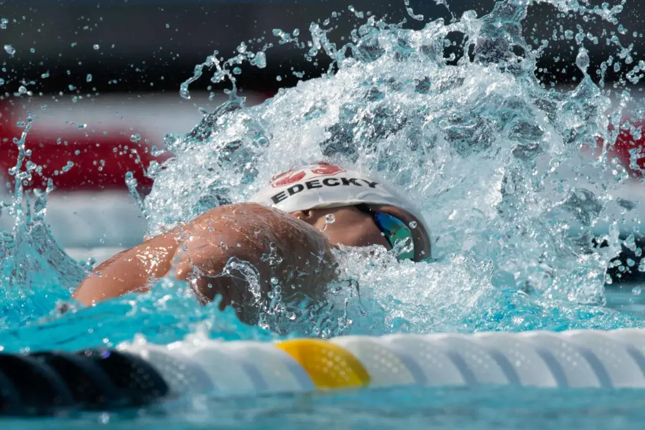 A swimmer powers through the water, creating a dramatic splash. This intense mid-distance swim workout shows dedication and strength.