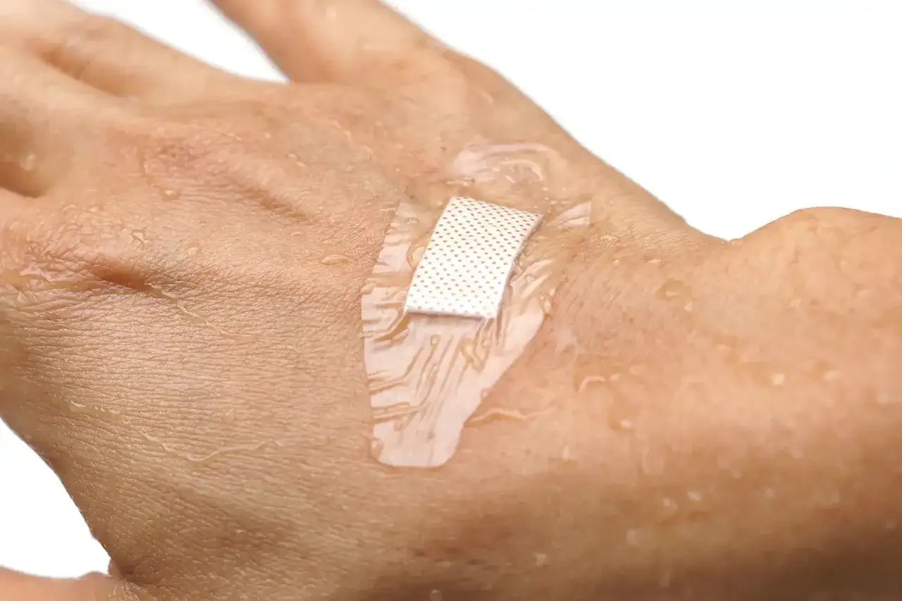 Water droplets on a bandaged hand. This image questions if you can swim with a burn, showing a waterproof bandage protecting a minor burn.