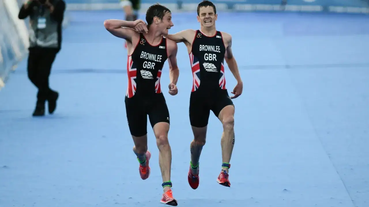 The Brownlee brothers, Alistair and Jonny, run together in their Great Britain triathlon suits, a moment of shared triumph.
