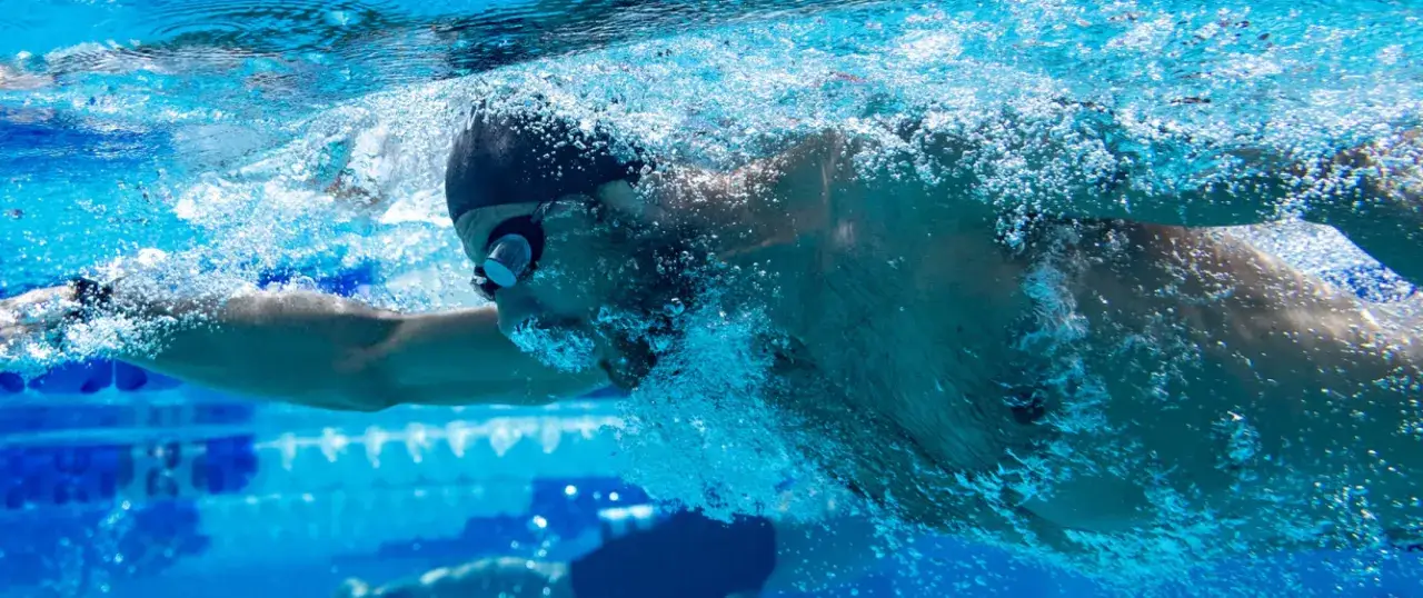Underwater shot of a swimmer, possibly Michael Phelps, with bubbles around his head. His focused expression hints at the intense effort and controlled michael phelps heart rate required for peak performance.