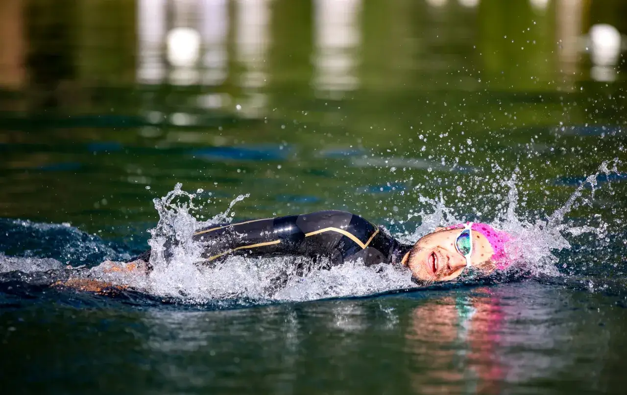 A determined swimmer powers through the water, goggles on, in an intense iron man race.
