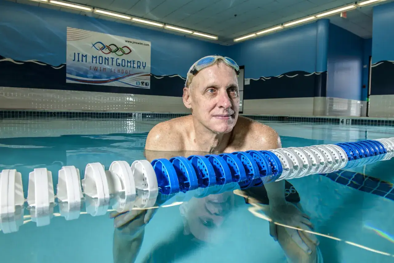 A man in goggles stands in a pool at Jim Montgomery Swim School, ready for his next lesson.