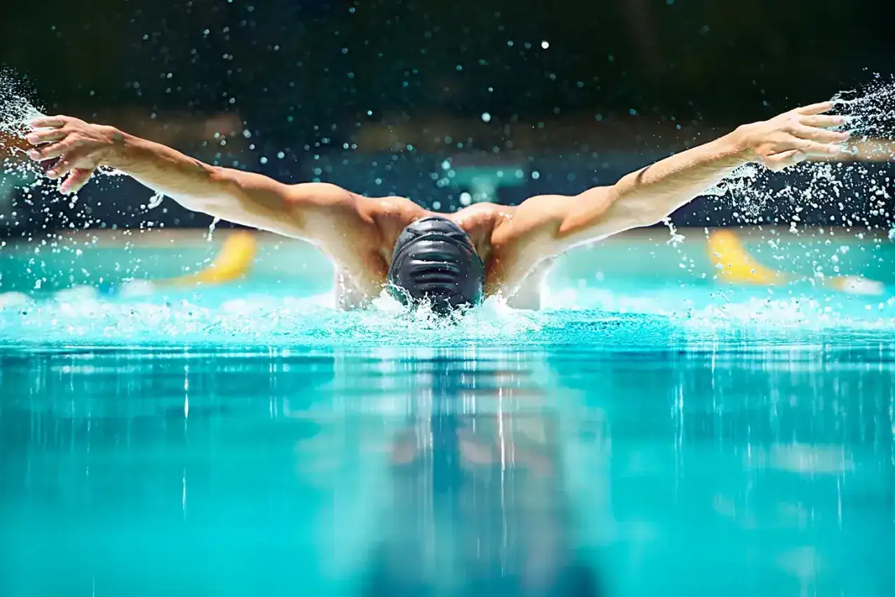 A swimmer's powerful butterfly stroke, with arms extended and water splashing, captures the essence of butterfly breathing.