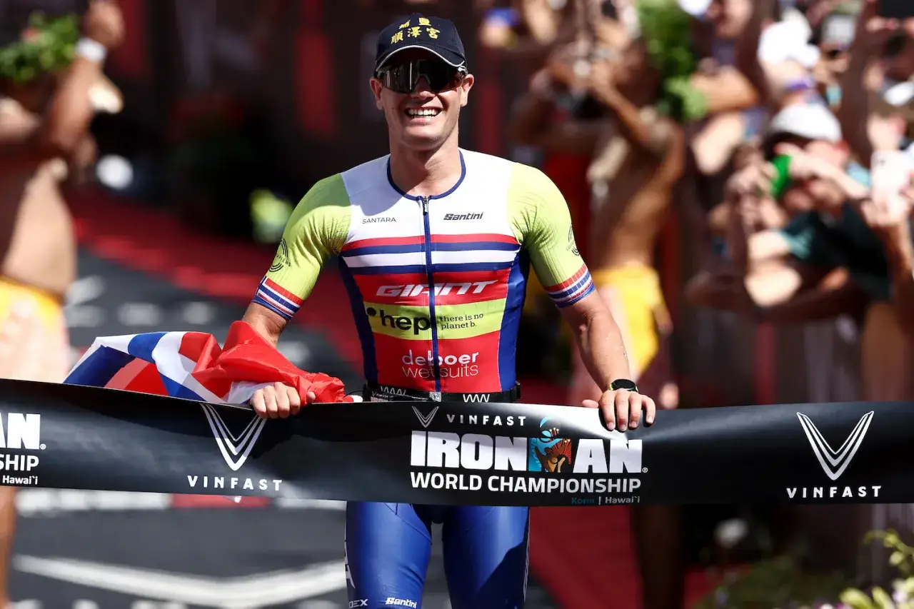 Gustav Iden crosses the finish line at the Ironman World Championship, beaming with pride and holding the Norwegian flag.