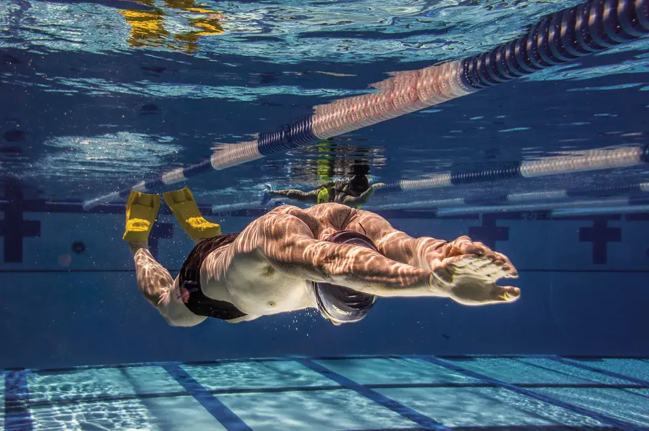 Underwater view of a swimmer with yellow fins performing fun swim drills in a pool lane.