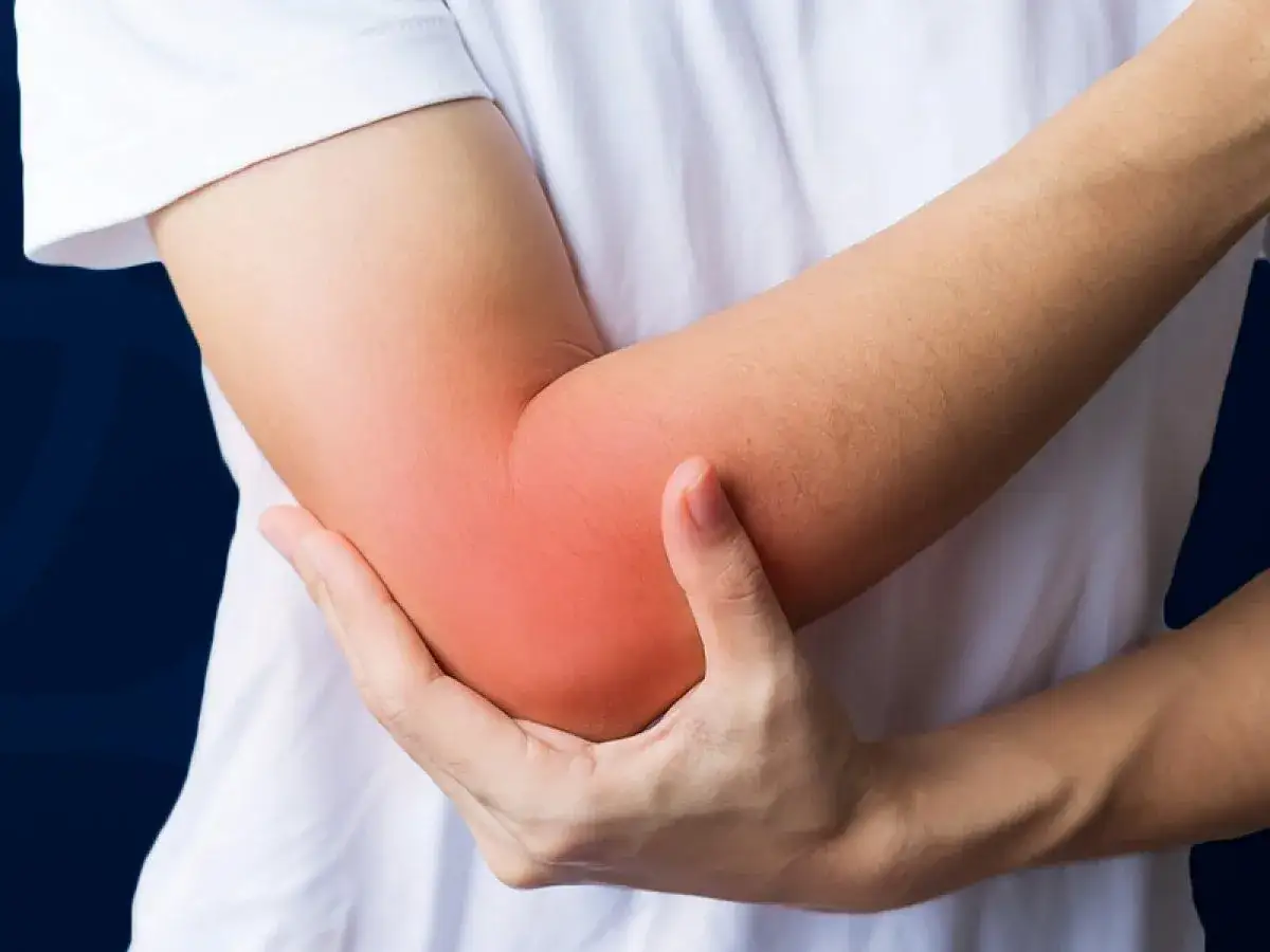 A person holds their elbow, which is highlighted in red, indicating pain. This could be a sign of swimmers elbow.