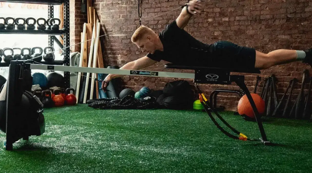 Swimmer performing mobility exercises on a SwimErg machine, strengthening core and improving shoulder range of motion.
