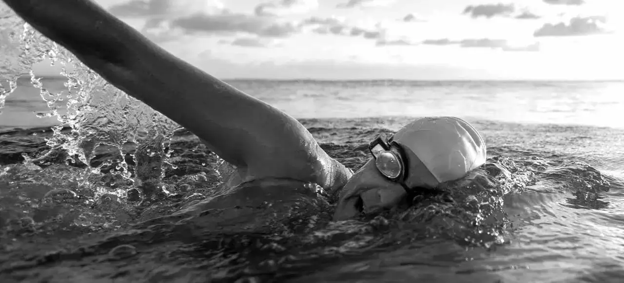 A swimmer, looking like an iron man, powers through the water, creating a splash.