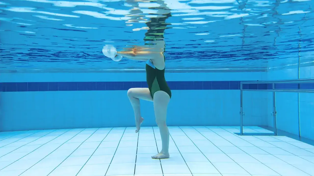 Underwater view of a person performing aqua jogging with weights, their legs bent and arms extended.