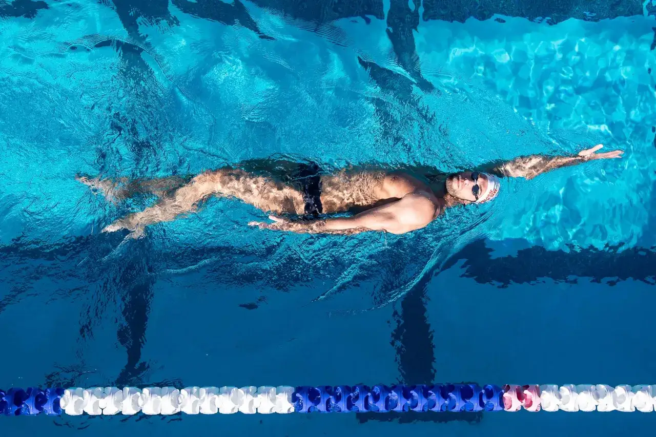 Swimmer demonstrating backstroke tips, with arms extended and body streamlined for efficient movement through the water.
