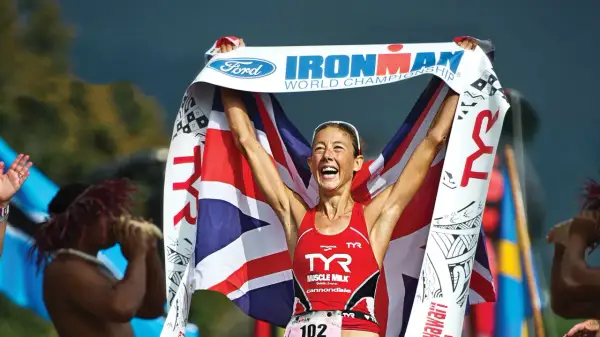 Chrissie Wellington celebrates her Ironman World Championship win, draped in the Union Jack and holding the Ford Ironman banner.