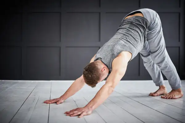 Man in downward-facing dog pose, a key stretch for yoga for triathletes, improving flexibility and recovery.