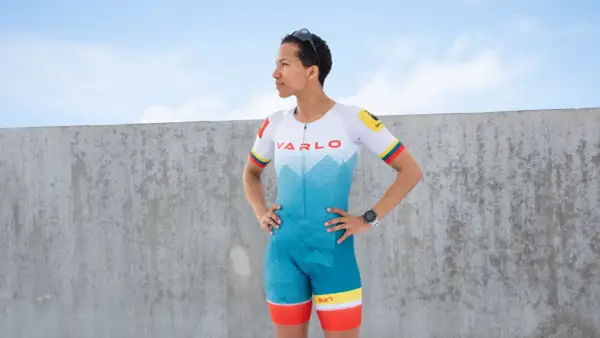 A woman in a vibrant blue and white triathlon suit, ready for competition. This is what to wear for a triathlon.