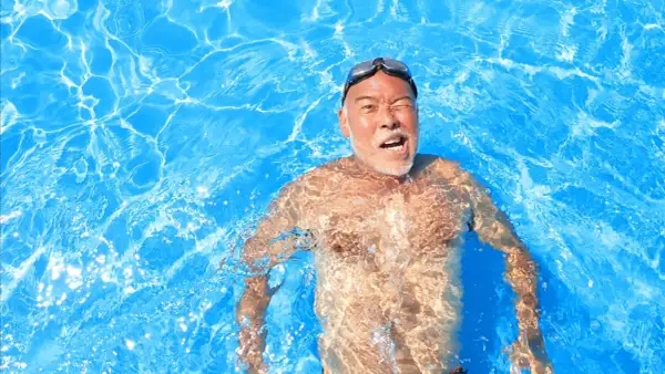 Man in pool, goggles on, with a surprised expression, experiencing immersion diuresis.